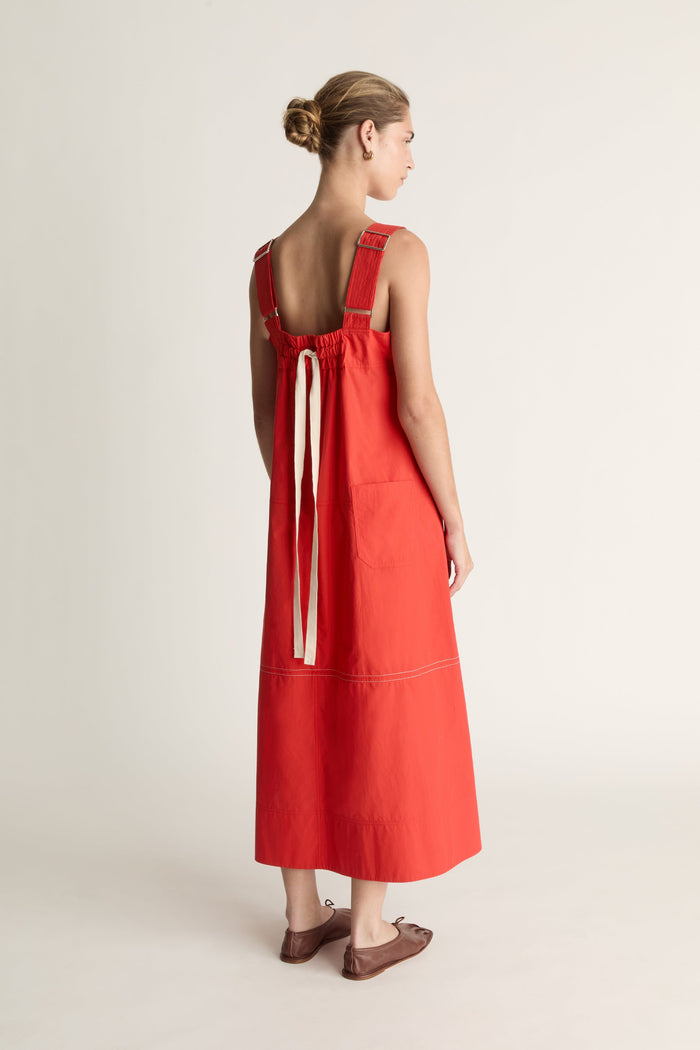 Woman wearing a red apron dress on a white background