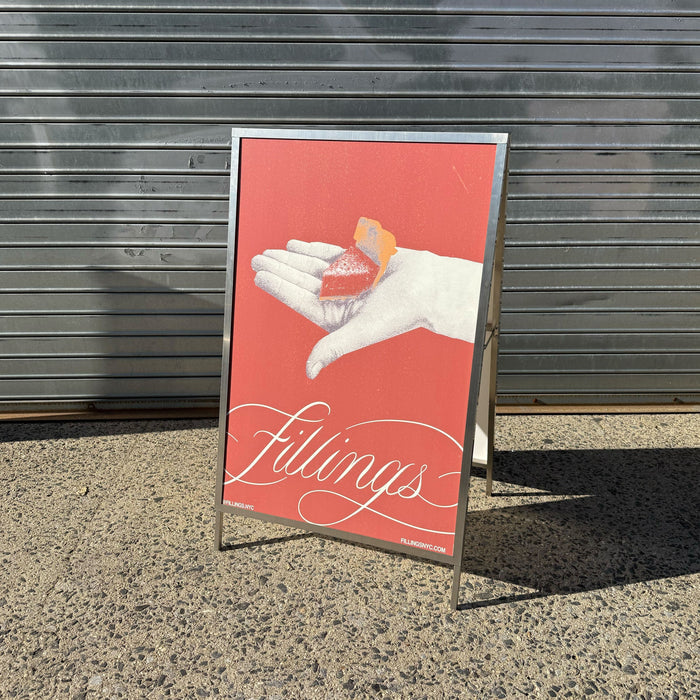 Metal A-frame sign holder displaying a red Fillings poster.