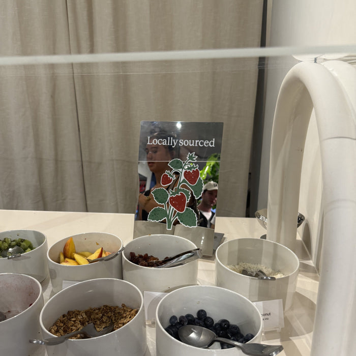 Mirrored tabletop sign with fruit illustrations beside bowls of food.