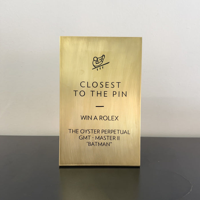 Brass tabletop sign with Closest to the Pin and Win a Rolex lettering.
