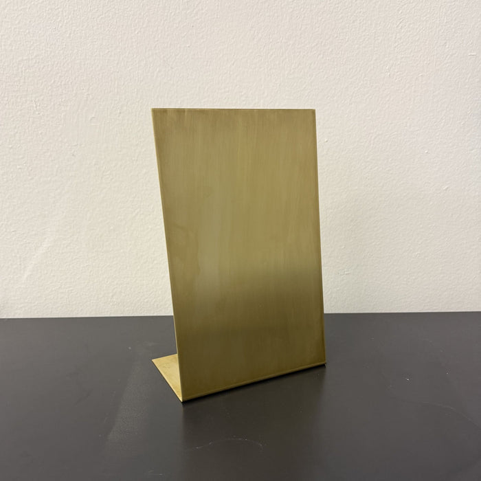 Angled view of a blank brass tabletop stand showing its flat base.