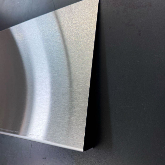 Close-up of the right edge and brushed finish of a stainless steel menu holder.
