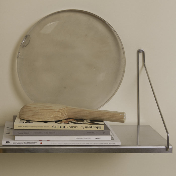 Stainless steel shelf displaying a tray, books, and a wooden brush.
