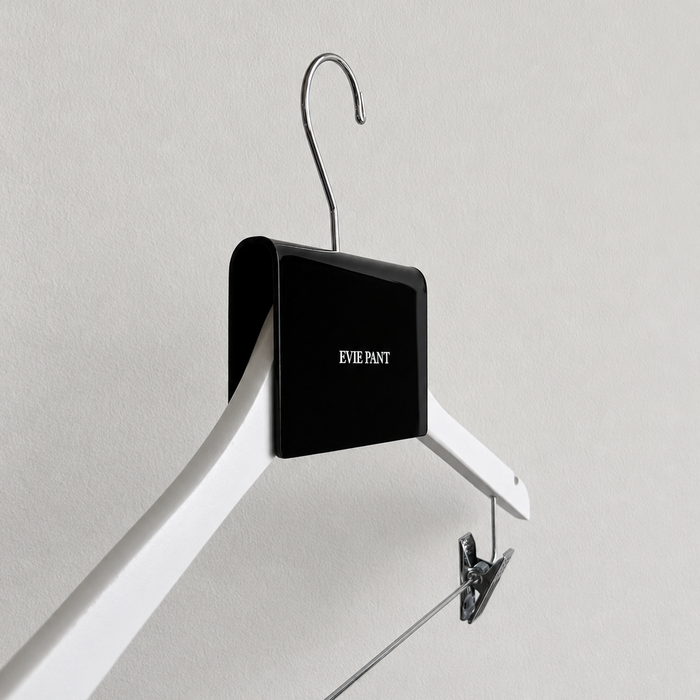 Side view of a black acrylic Evie Pant sign clip fitted over a hanger.