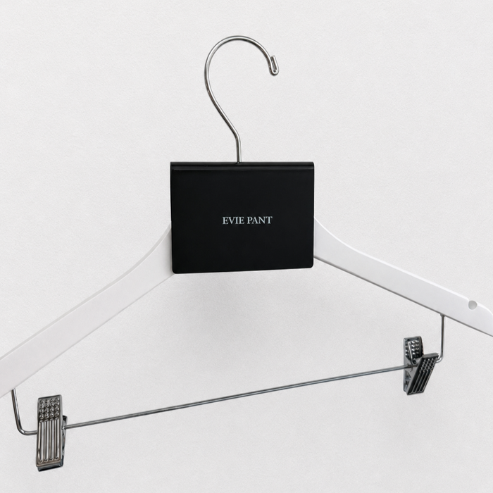Angled view of a black acrylic Evie Pant sign clip on a white hanger.