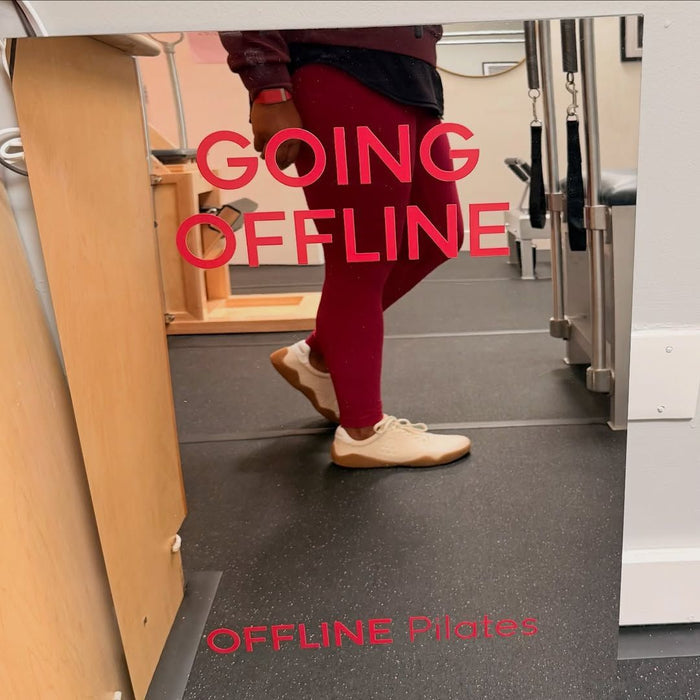Mirrored leaning panel sign with red Going Offline and Offline Pilates lettering.
