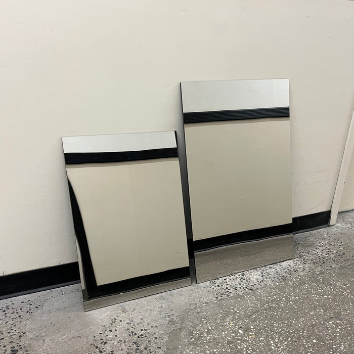 Two mirrored stainless steel leaning panel signs in different sizes.