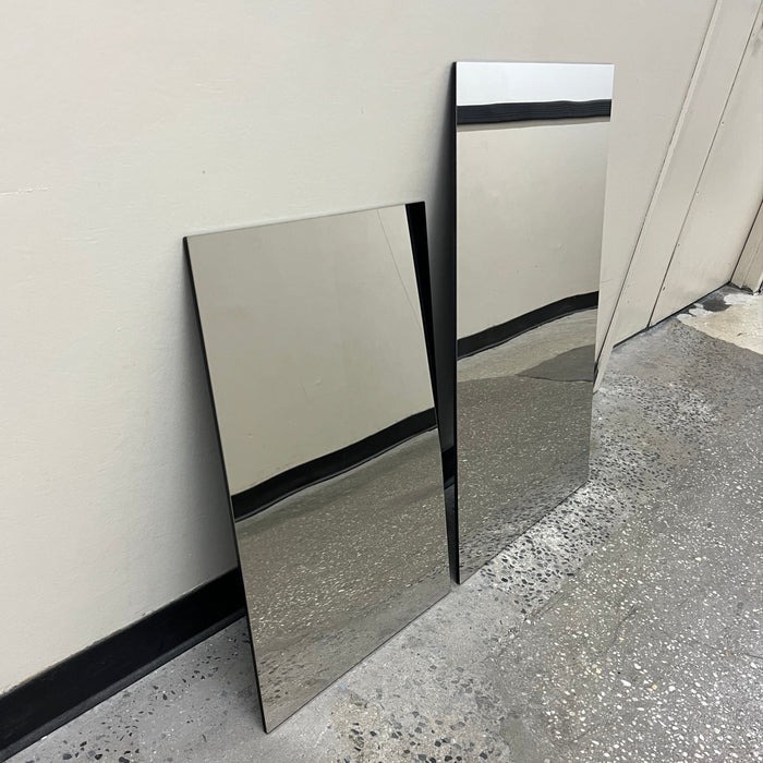 Angled view of two mirrored stainless steel panels leaning against a wall.