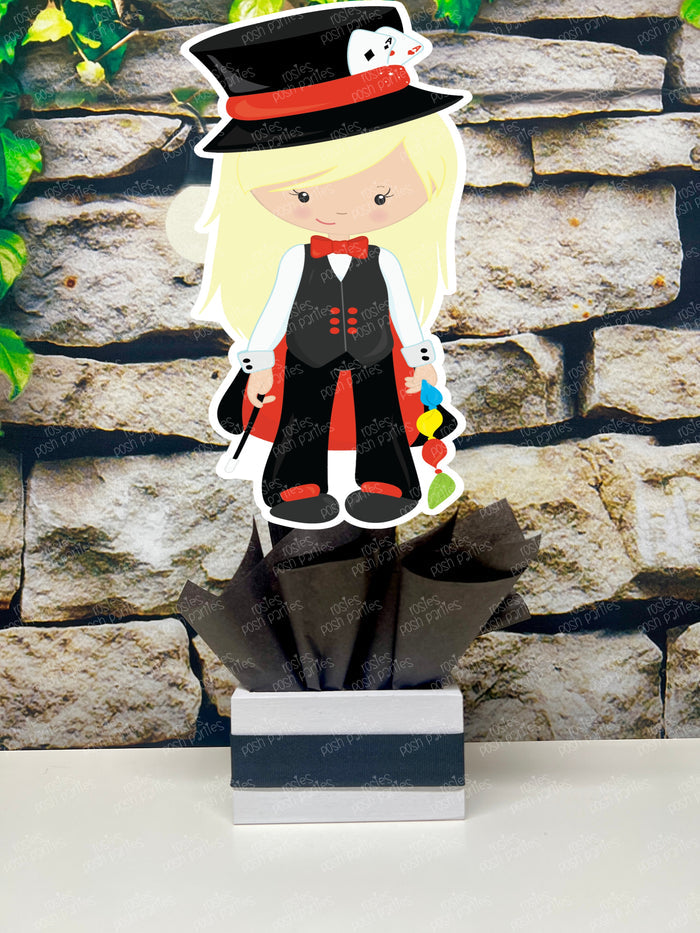 Kids birthday party magician themed centerpieces. The centerpieces feature illustrated cutouts including playing cards, a white rabbit in a tuxedo, a girl magician, a boy magician, a rabbit popping out of a top hat, and a magician's hat with a wand. Each cutout is set in a red, white, or black base filled with matching tissue paper. Receive fully assembled like pictured.