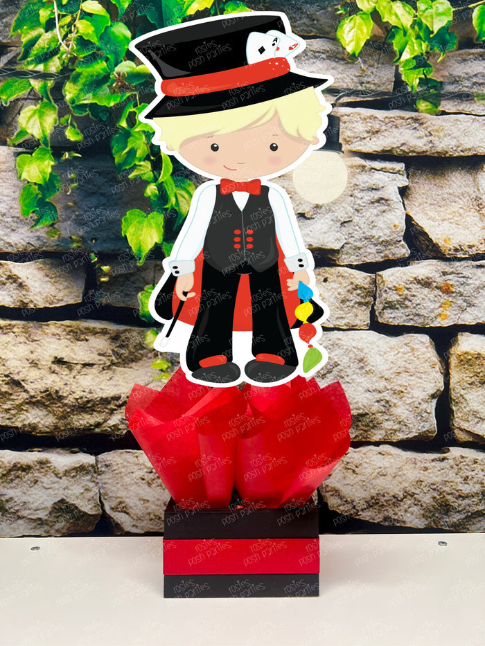 Kids birthday party magician themed centerpieces. The centerpieces feature illustrated cutouts including playing cards, a white rabbit in a tuxedo, a girl magician, a boy magician, a rabbit popping out of a top hat, and a magician's hat with a wand. Each cutout is set in a red, white, or black base filled with matching tissue paper. Receive fully assembled like pictured.