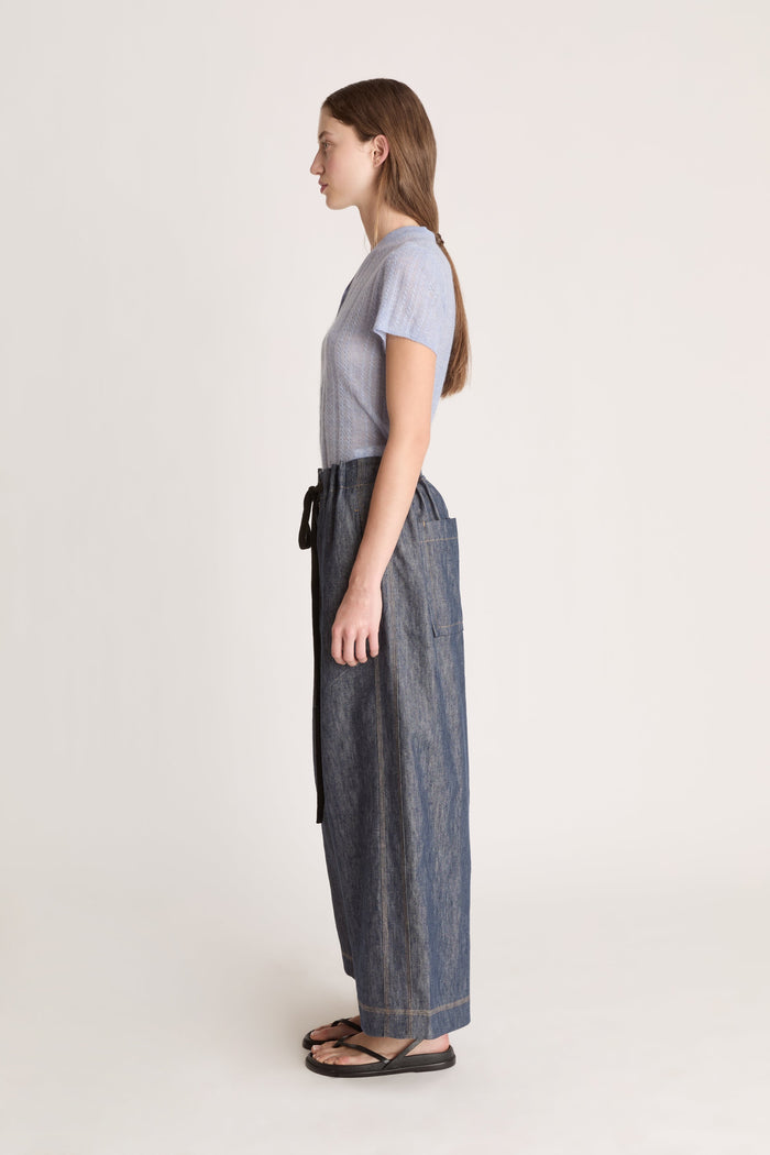 Woman wearing a light blue t-shirt and dark denim pants on a white background