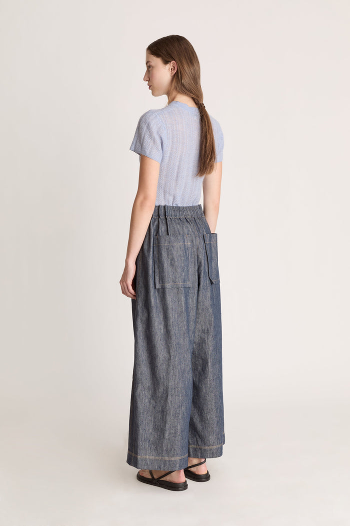 Woman wearing a light blue shirt and dark denim pants on a white background