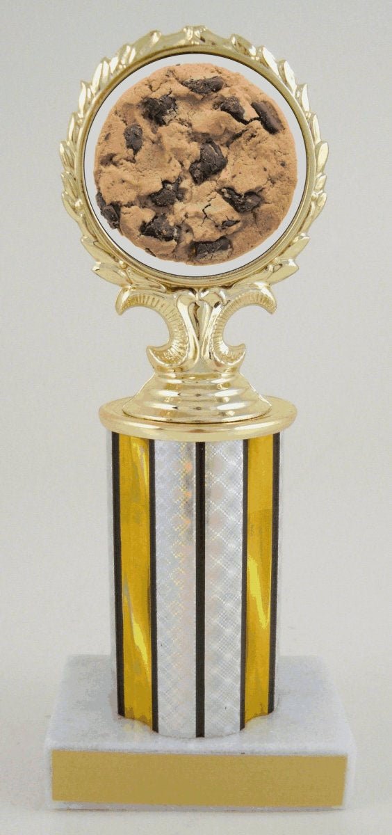 A novelty cookie-themed trophy with a gold-colored frame holding a chocolate chip cookie, mounted on a gold and silver striped column over a white marble base.