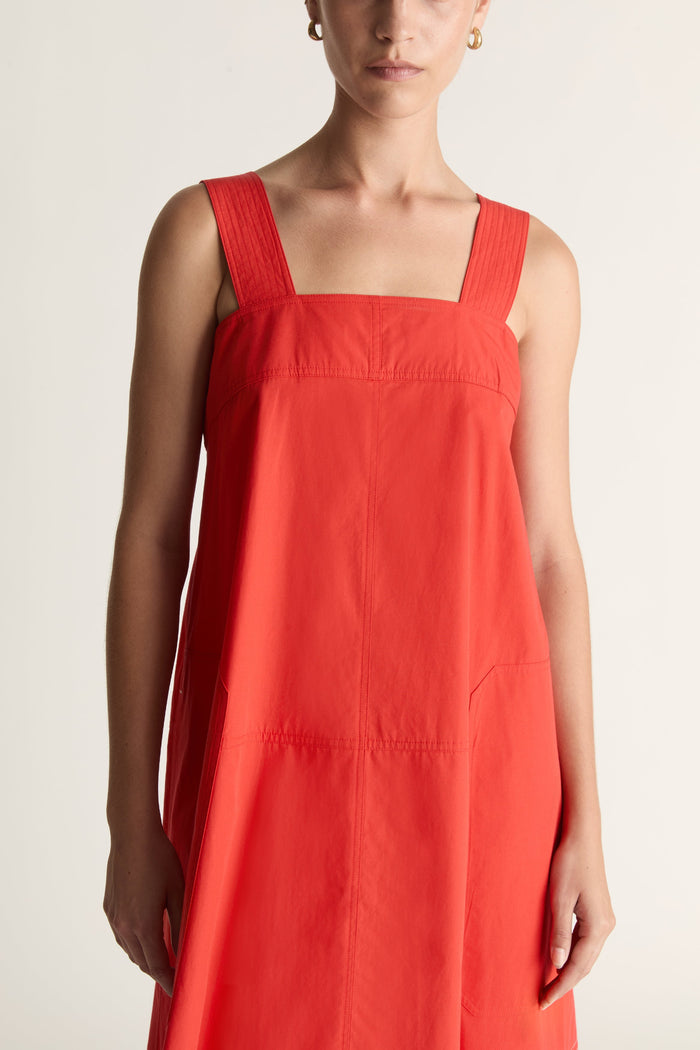 Woman wearing a red apron dress on a white background