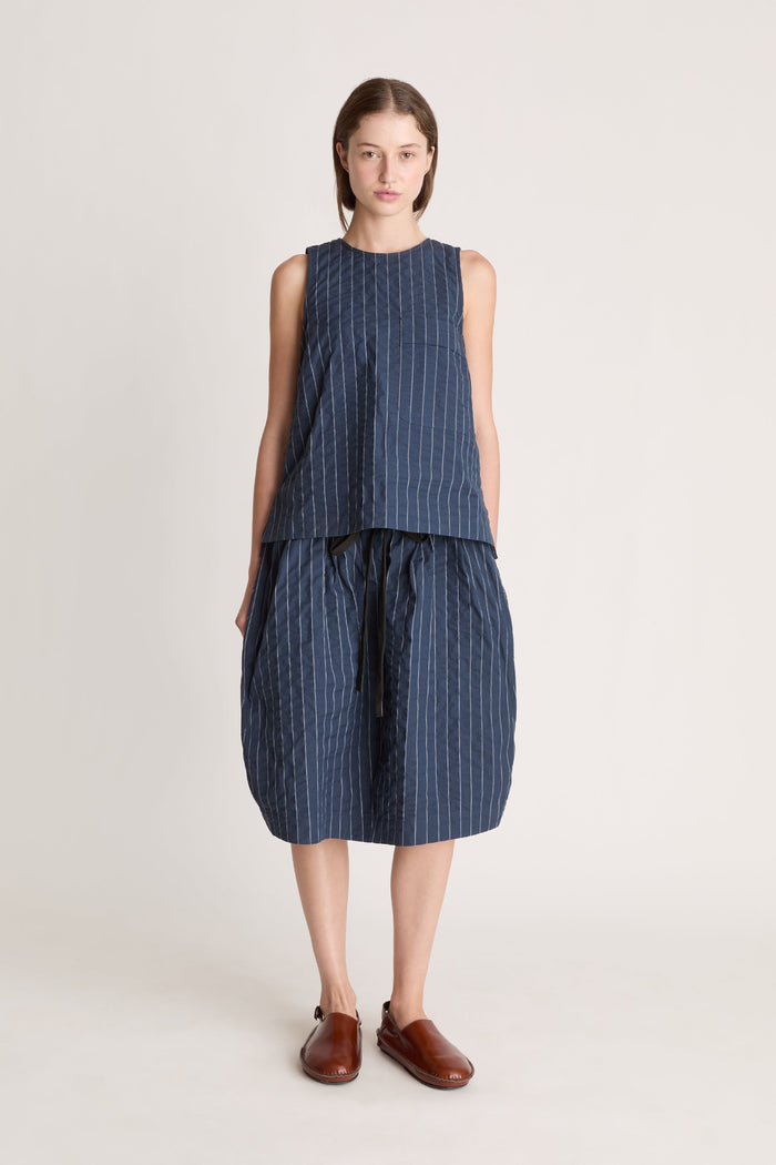 A woman wearing a blue striped top and skirt on a white background
