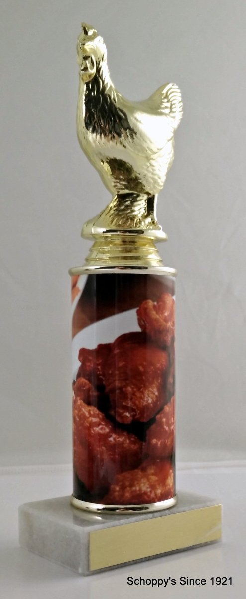 A trophy featuring a gold chicken figure on top of a column, with a base containing images of chicken wings. On top a white marble base with gold engraving plate.