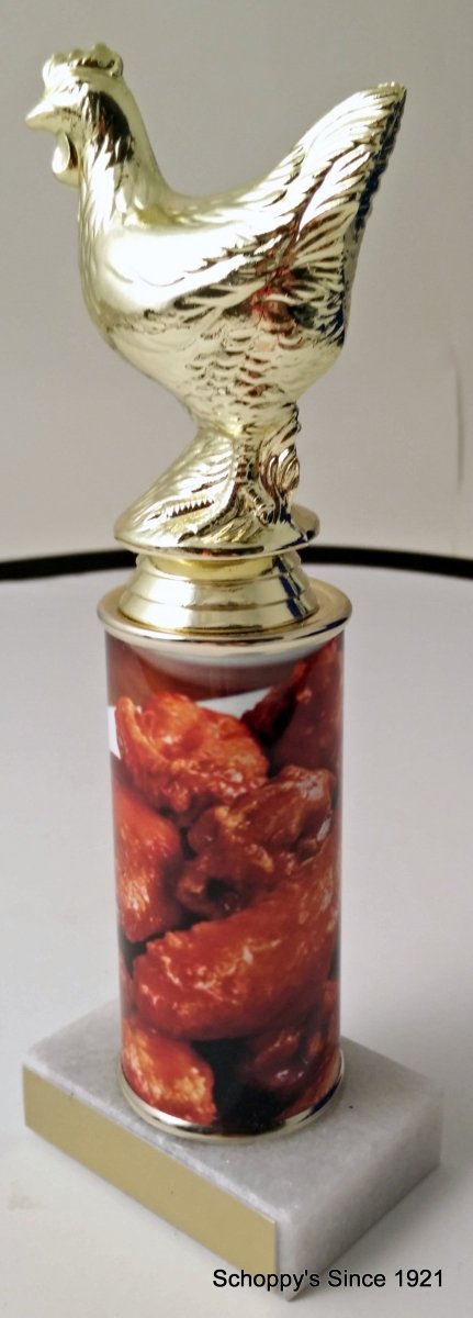 A trophy featuring a gold chicken figure on top of a column, with a base containing images of chicken wings. On top a white marble base with gold engraving plate.