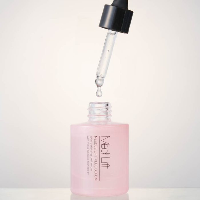 Pink serum bottle with dropper on a light gray background