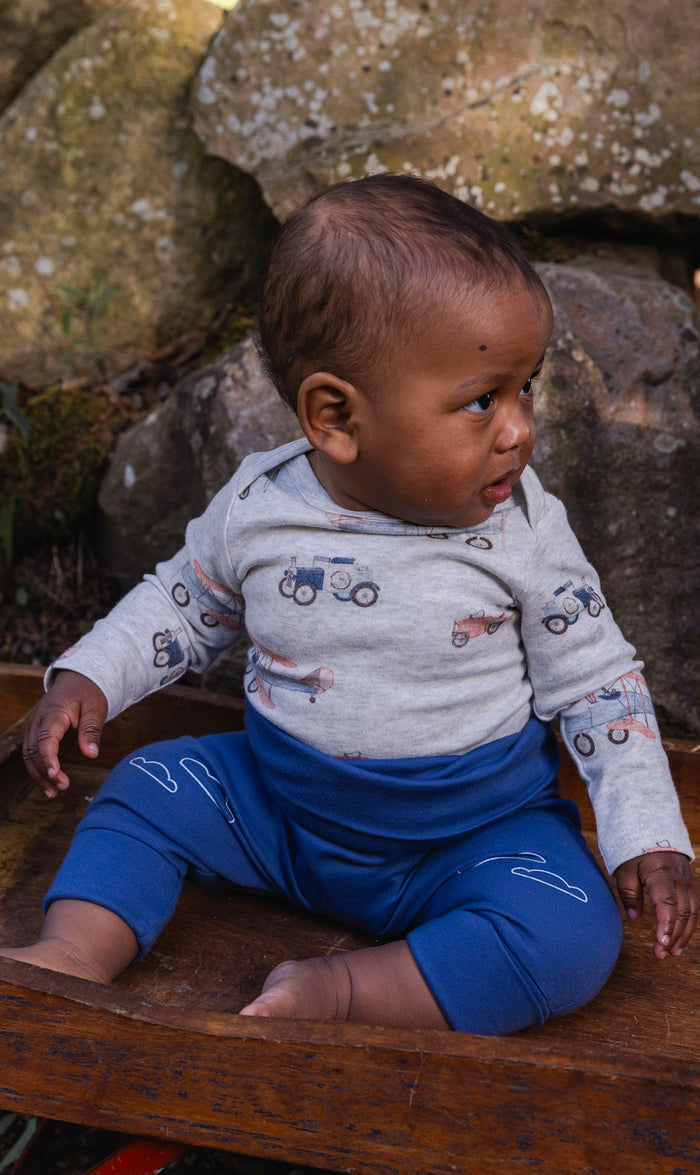 Baby wearing the Deux par Deux organic cotton onesie with beige vintage airplane print, view 2