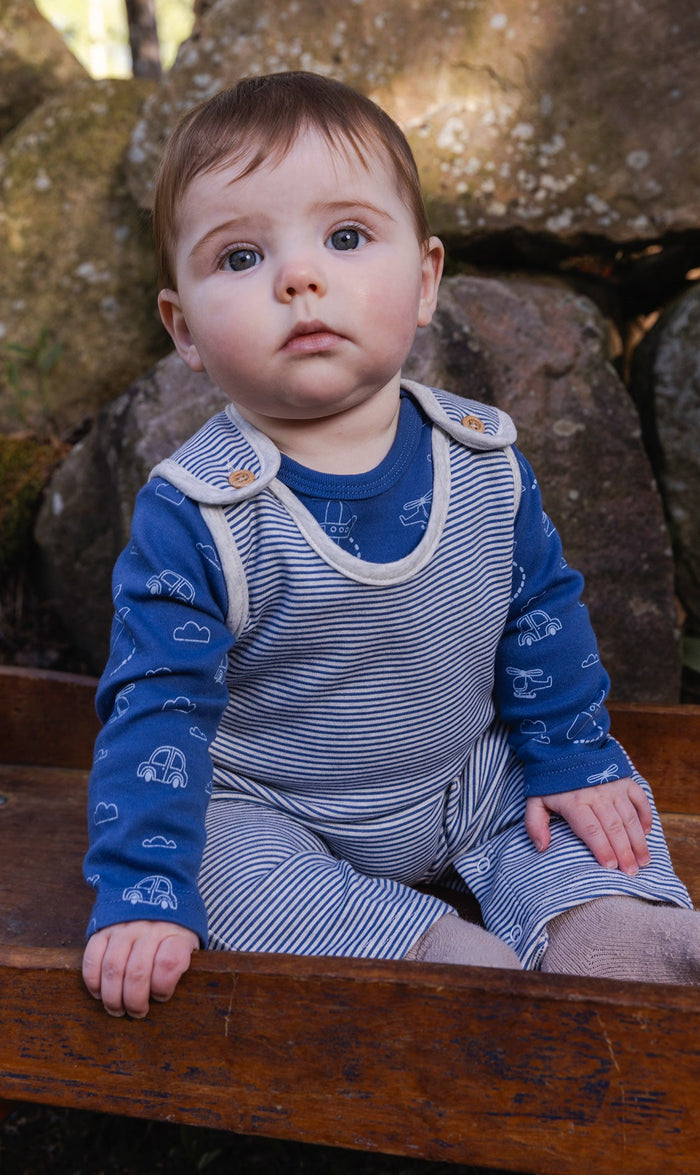 Baby wearing the Deux par Deux organic cotton set with blue transportation-print onesie and striped overalls, view 2