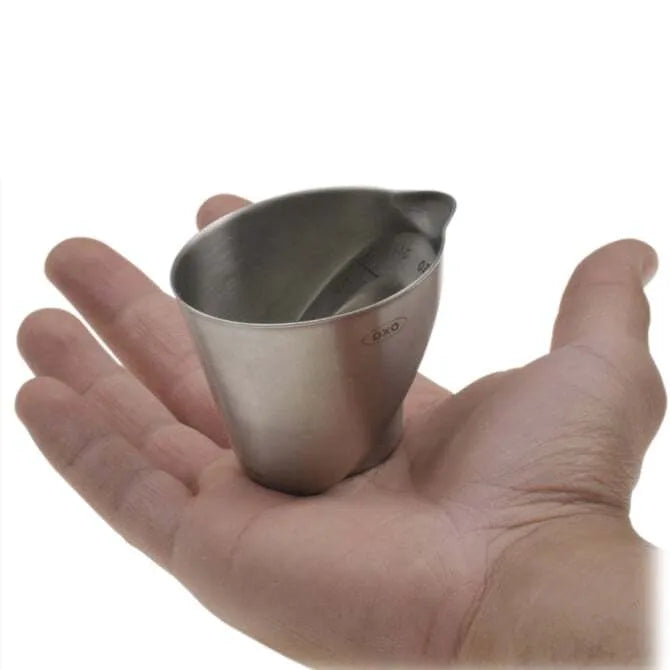 Stainless Steel Oxo Angled Measuring Cup - 2 oz handheld on white background.