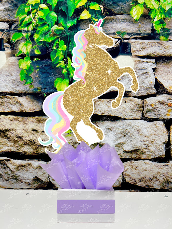 fully decorated unicorn theme table centerpieces for a birthday party or baby shower. Each centerpiece features a cute, pastel color unicorn with printed glitter accents, placed in a white box with colorful tissue paper in shades of blue, purple, mint green, and pink.