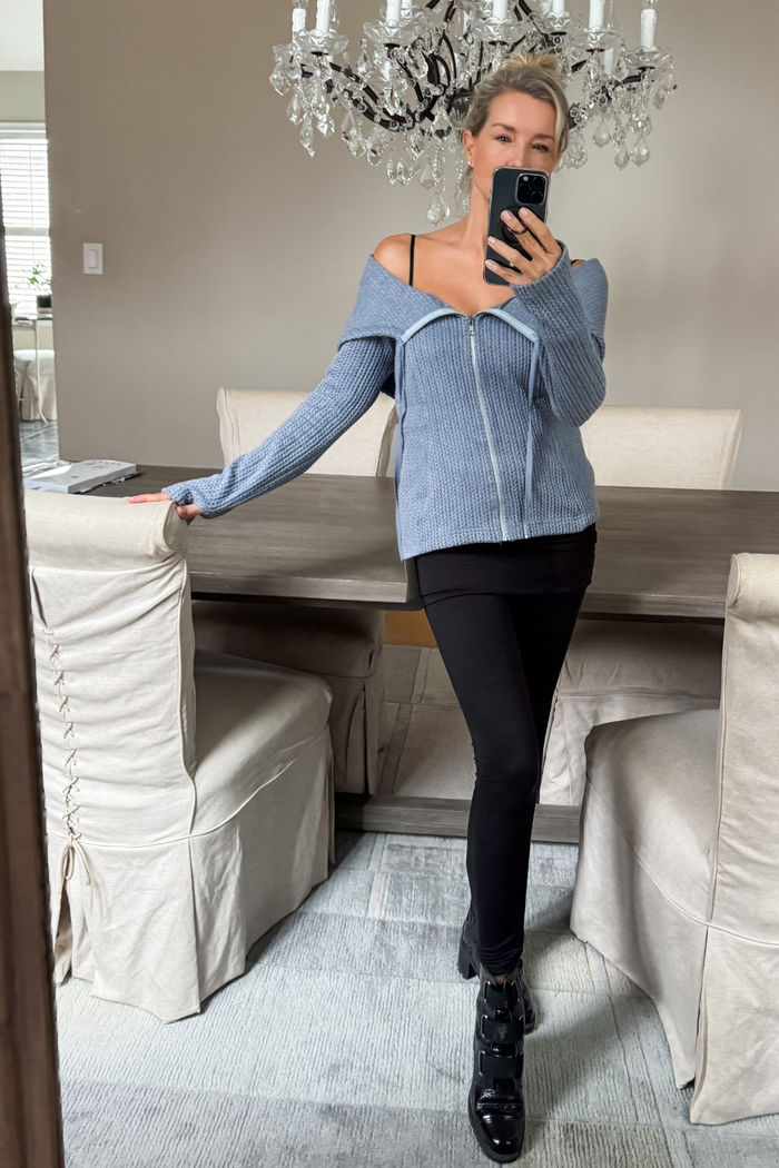 Diane Kroe wearing a wearing a blue knitted convertible hoodie and black pants
