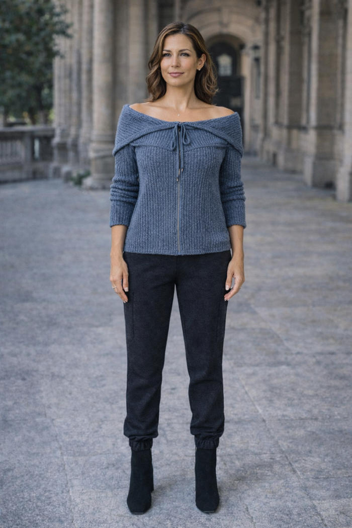 Woman wearing a blue off-shoulder knitted convertible hoodie and the midnight denim cargo pants standing in an outdoor setting
