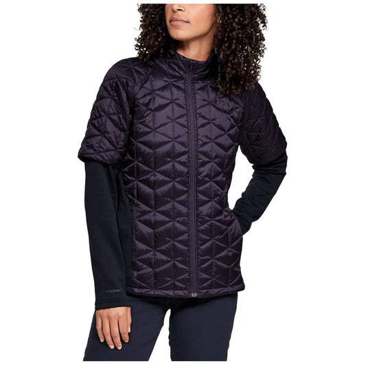 Under Armour Ladies ColdGear Reactor Hybrid Jacket A person is wearing a short-sleeved, quilted purple jacket over a long-sleeved black shirt in a neutral setting, showcasing a stylish, outdoor-ready look suitable for cooler temperatures.