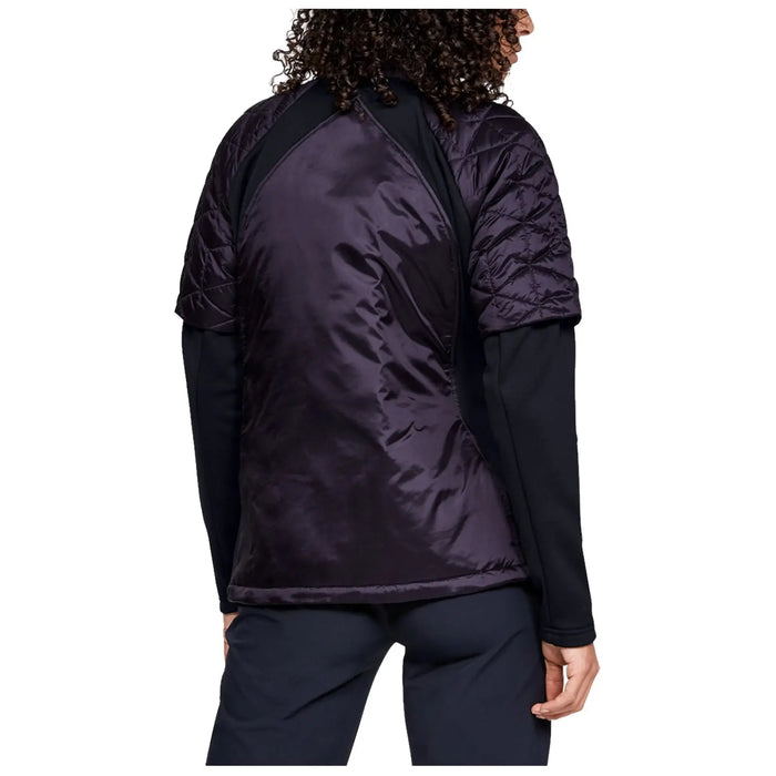 A person wearing a black long-sleeve shirt and a quilted purple jacket with short sleeves stands with their back partially visible in a neutral background.