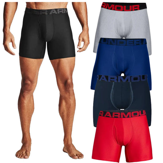 A male model stands barefoot wearing black fitted boxers showcasing his legs while four additional pairs of boxers in various colors are displayed beside him on a plain background.